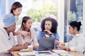 Conquistar um novo cliente custa 5 vzes mais. Na imagem, um time de mulheres de diferentes etnias trabalha junto