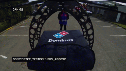 Vídeo de uma pessoa pilotando um Drone com o controle remoto. O Drone está carregando uma pizza para entrega. 