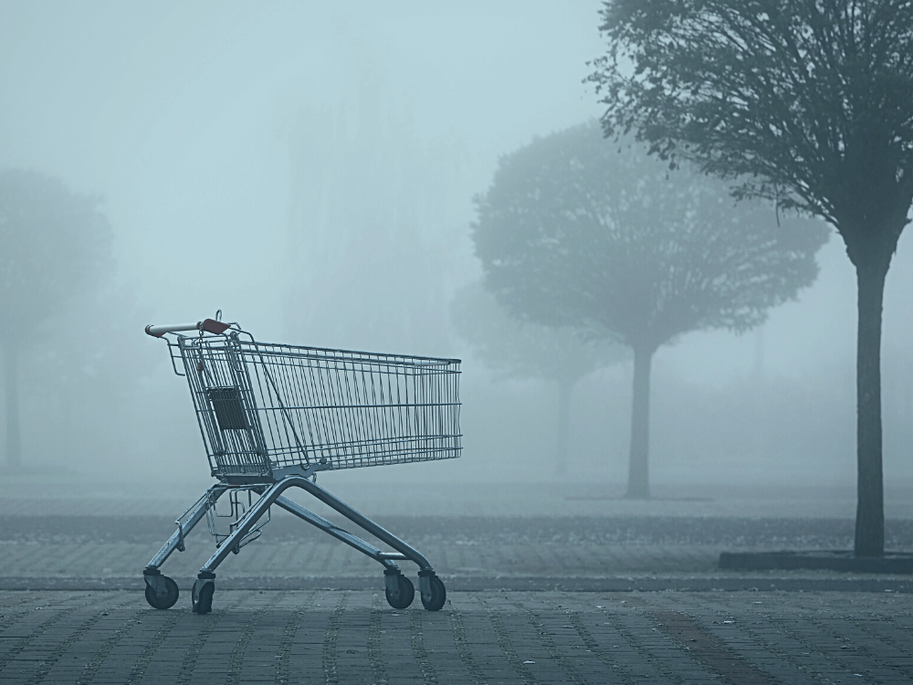 Carrinhos abandonados: imagem de um carrinho de supermercado em um estacionamento vazio com árvores em meio a um nevoeiro