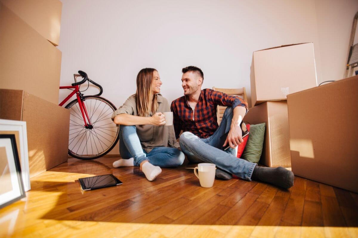Moradia por assinatura: casal sentado em sala de estar com caixas de mudança