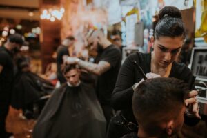 mulher corta cabelo em salão de barbearia